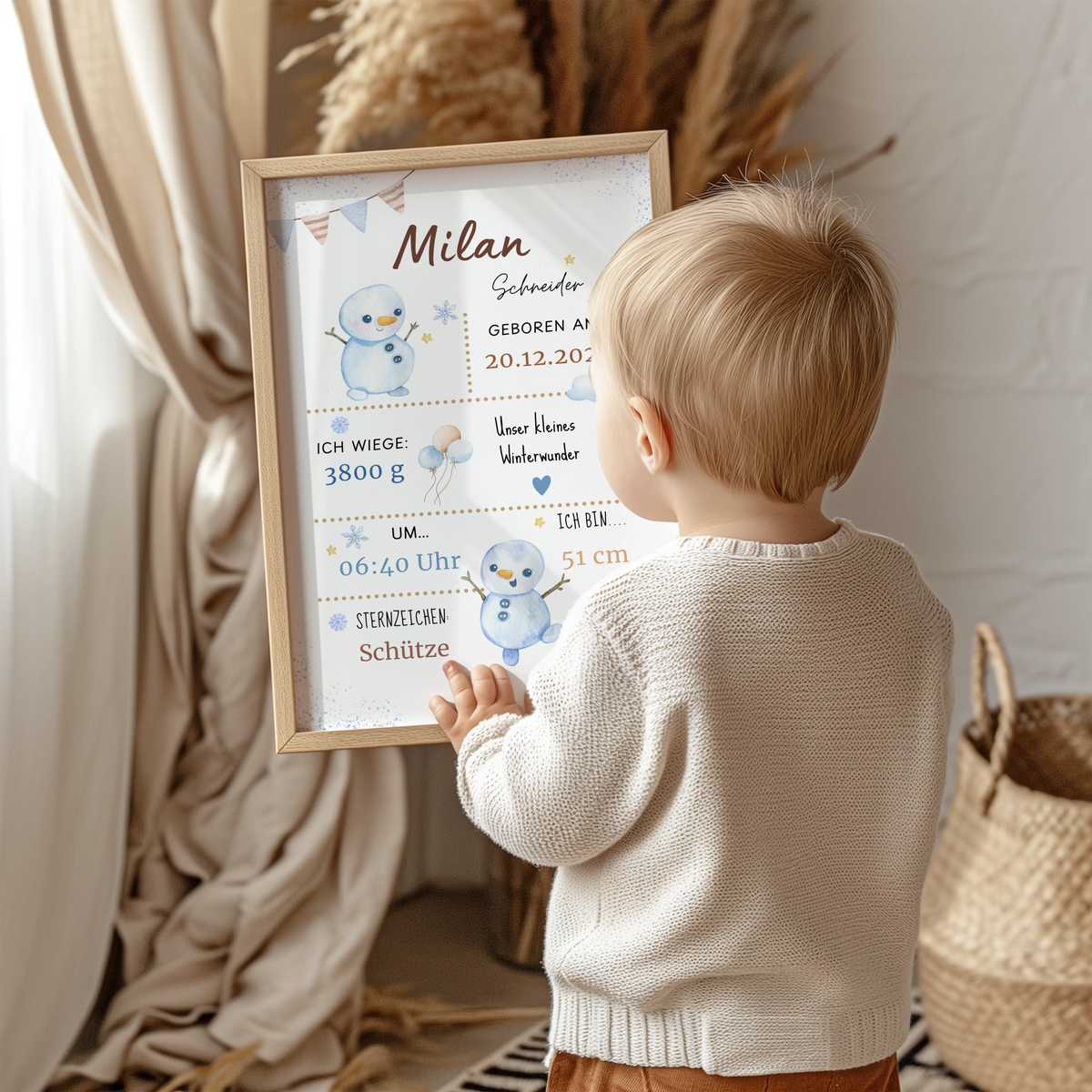 Personalisiertes Geburtsposter Winterbaby mit Schneemännern, Kinder hält das Poster in der Hand.